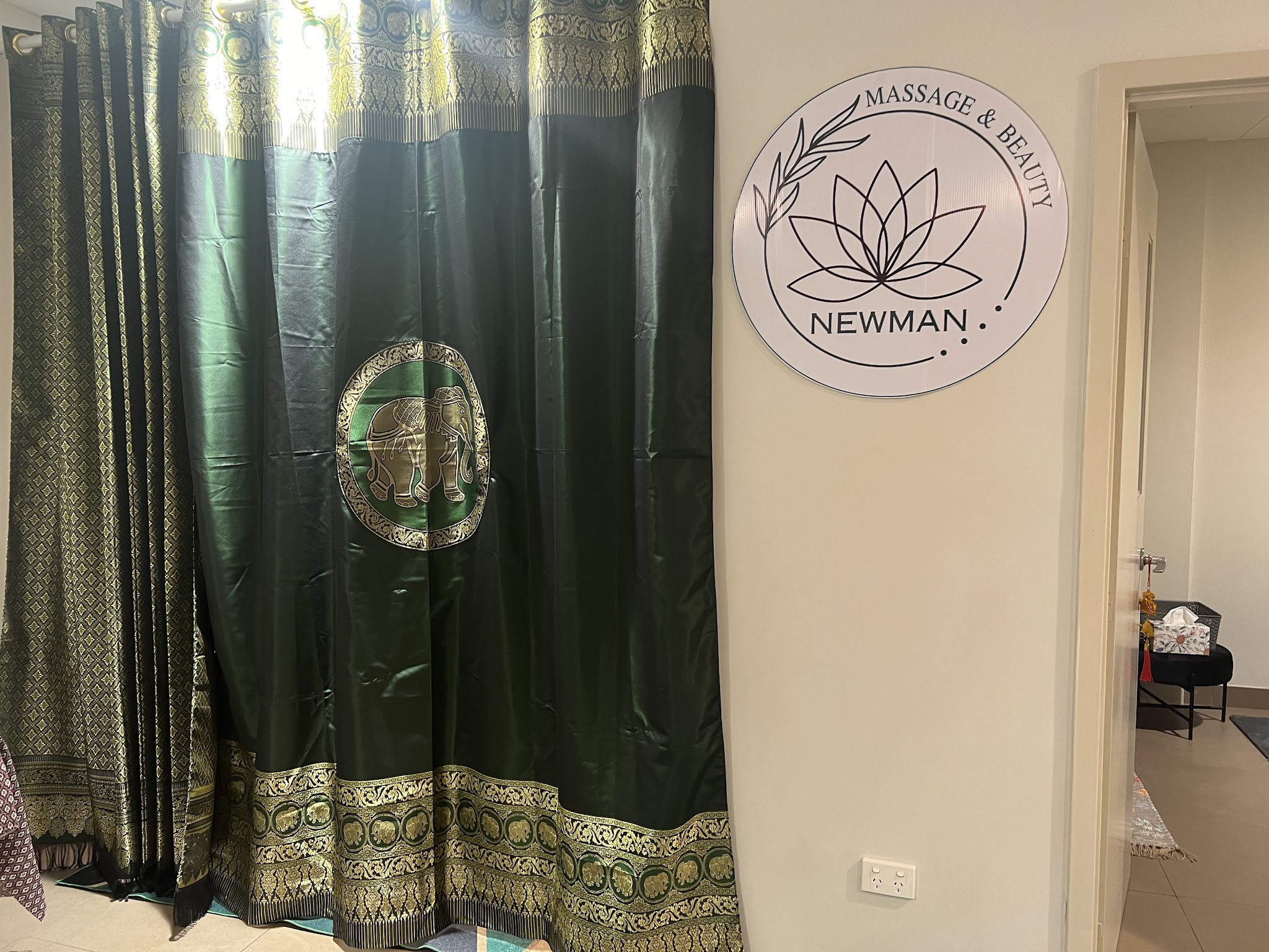 A green and gold Thai silk curtain at the entrance to the treatment room, beside the Newman Massage and Beauty wall sign